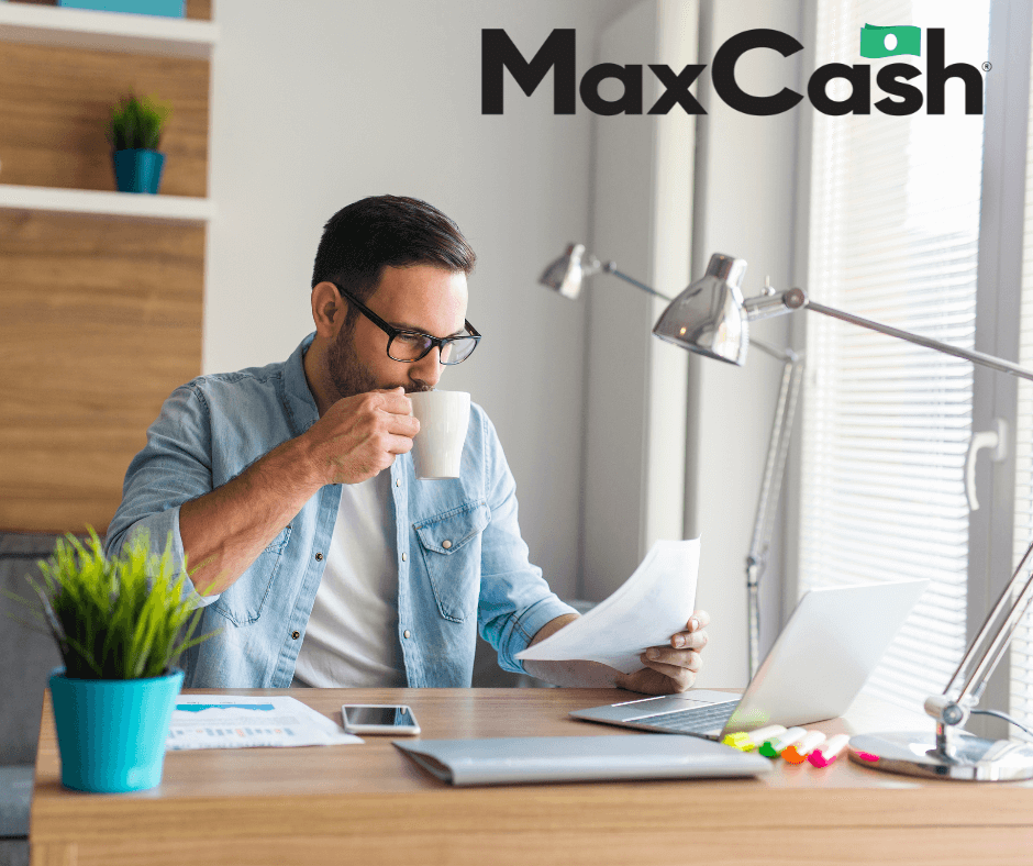 Man holding a cup of coffee looking at a paper