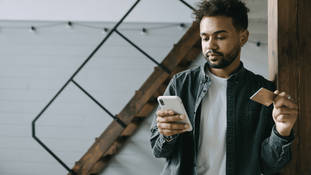Man holding a credit card and a phone to make a purchase