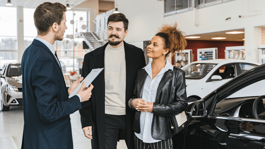 A couple standing in front of a car salesman in a showroom