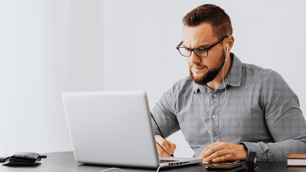 A man with headphones on browsing on the computer
