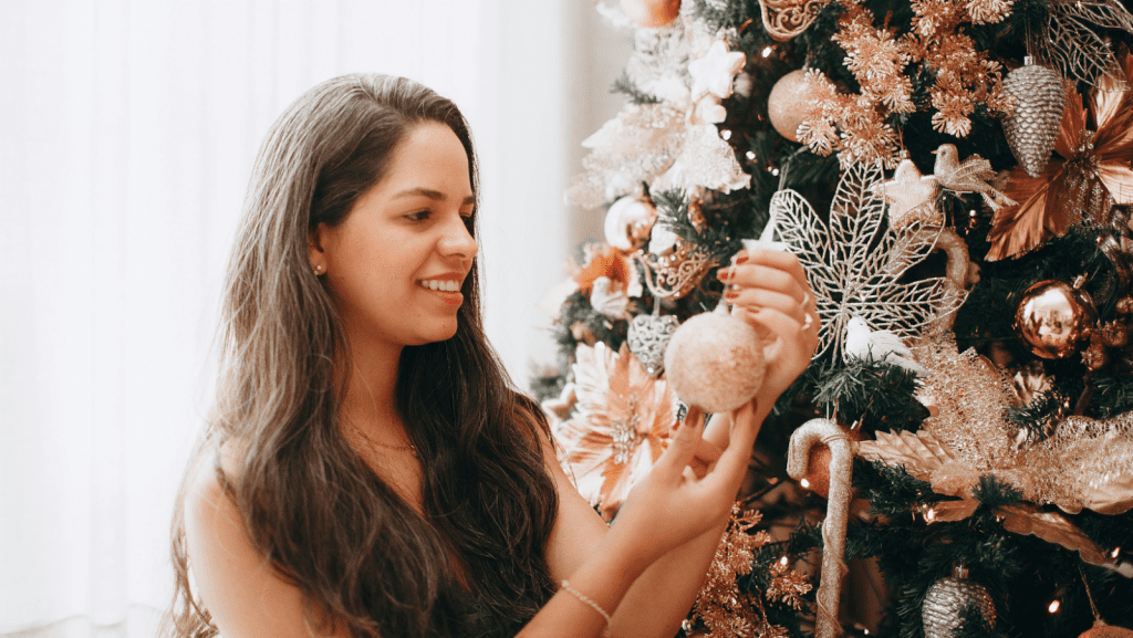 Woman holding an ornament next to a Christmas tree