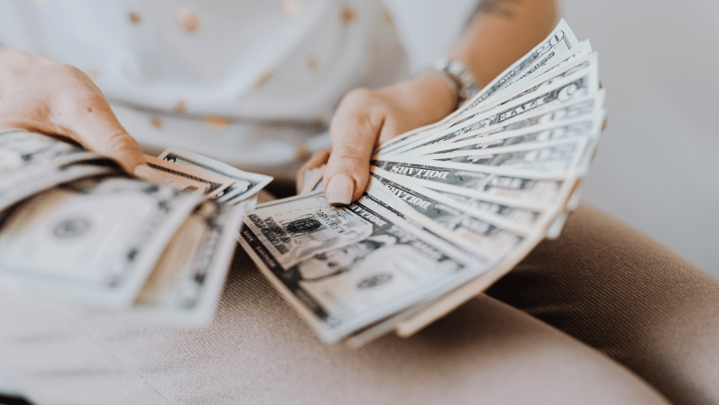 Woman with acrylic nails holding a fan of money