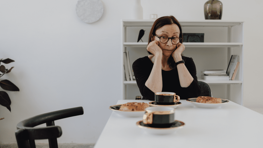 Woman sitting down at a breakfast table with a thoughtful expression
