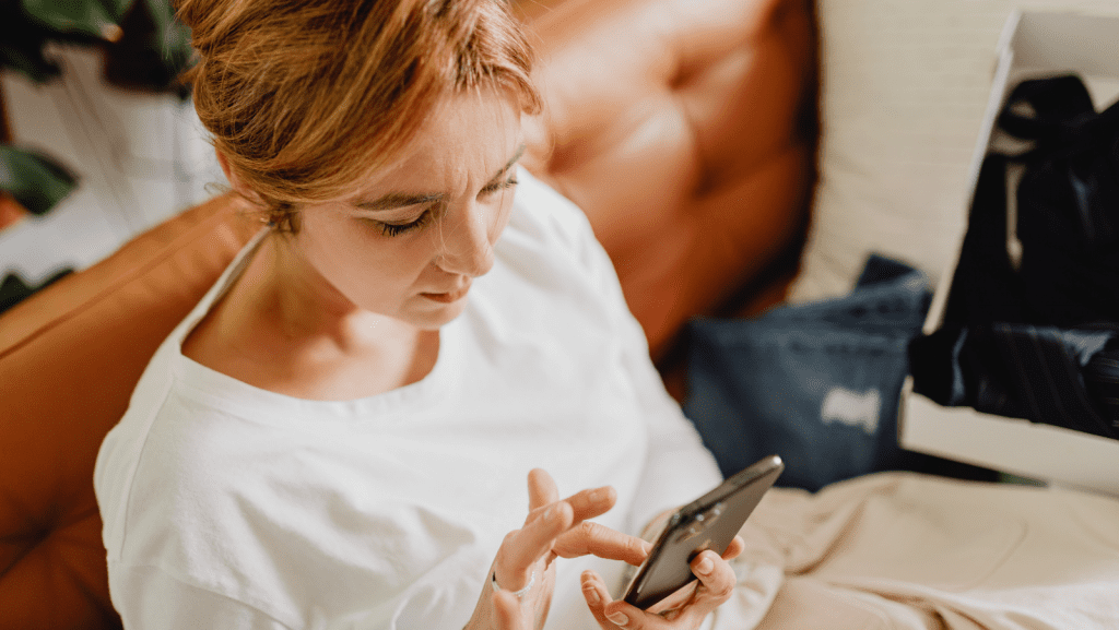 Woman looking at her phone sitting next to the bed