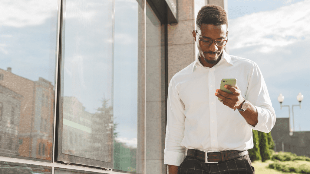 Man looking at phone outside near a window