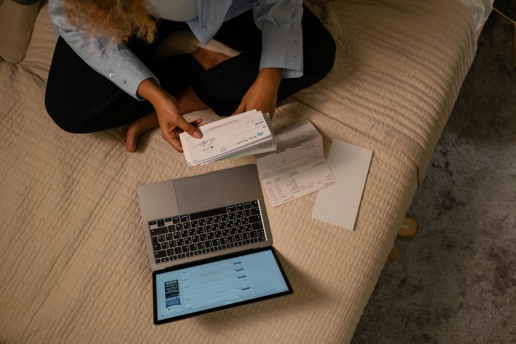 Woman sitting on bed with a check in her hand